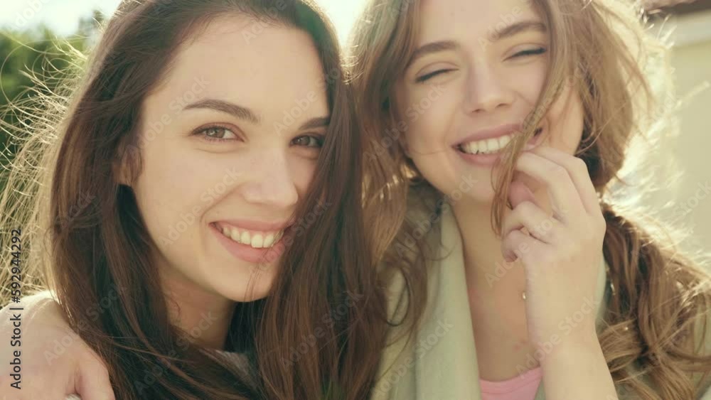 Two young beautiful smiling hipster girls in trendy clothes. Sexy carefree women posing on street background. Positive models Two young beautiful smiling hipster girls in trendy clothes. Sexy carefree women posing on street background. Positive models