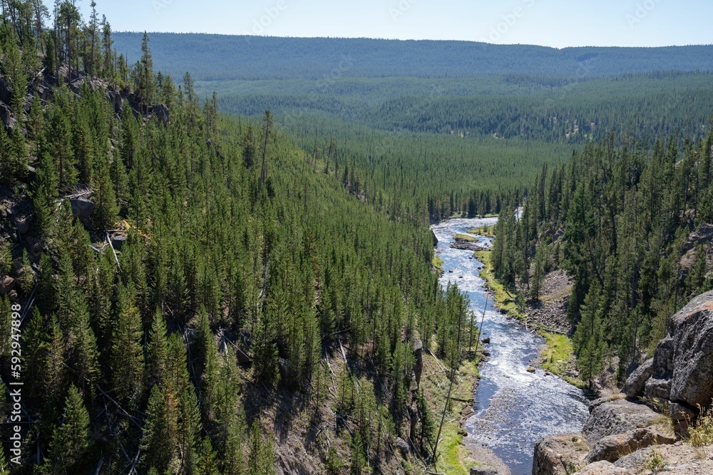 Landscape of waterfall flowing between rocks and green trees on a sunny day Landscape of waterfall flowing between rocks and green trees on a sunny day