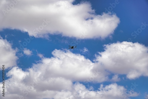 Low-angle view of a drone flying in the air against a cloudy blue sky