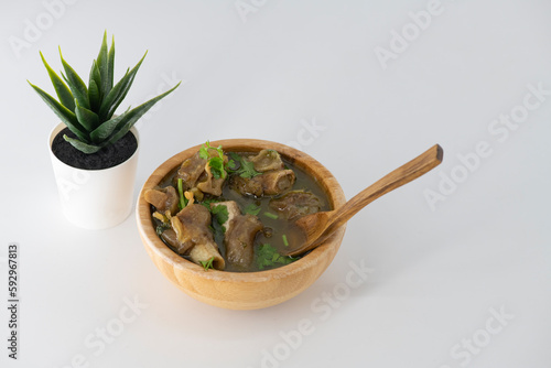 Fresh spicy lamb paya soup in a wooden bowl and ready to eat. Home made mutton soup called paya or attukaal soup in south india. Mutton soup in wooden bowl..