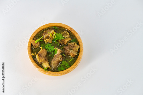 Fresh spicy lamb paya soup in a wooden bowl and ready to eat. Home made mutton soup called paya or attukaal soup in south india. Mutton soup in wooden bowl. photo