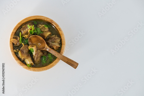 Fresh spicy lamb paya soup in a wooden bowl and ready to eat. Home made mutton soup called paya or attukaal soup in south india. Mutton soup in wooden bowl..