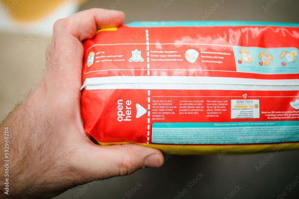 Frankfurt, Germany - Mar 18, 2023: POV male hand holding package of new  Pampers baby-dry pants