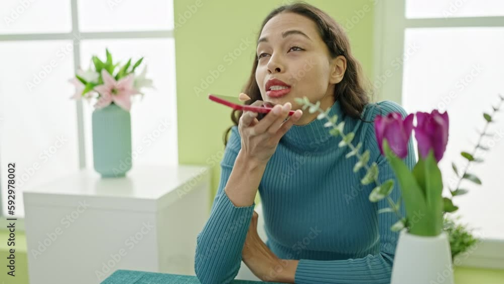 Young beautiful hispanic woman sending voice message by smartphone sitting on table at home Young beautiful hispanic woman sending voice message by smartphone sitting on table at home