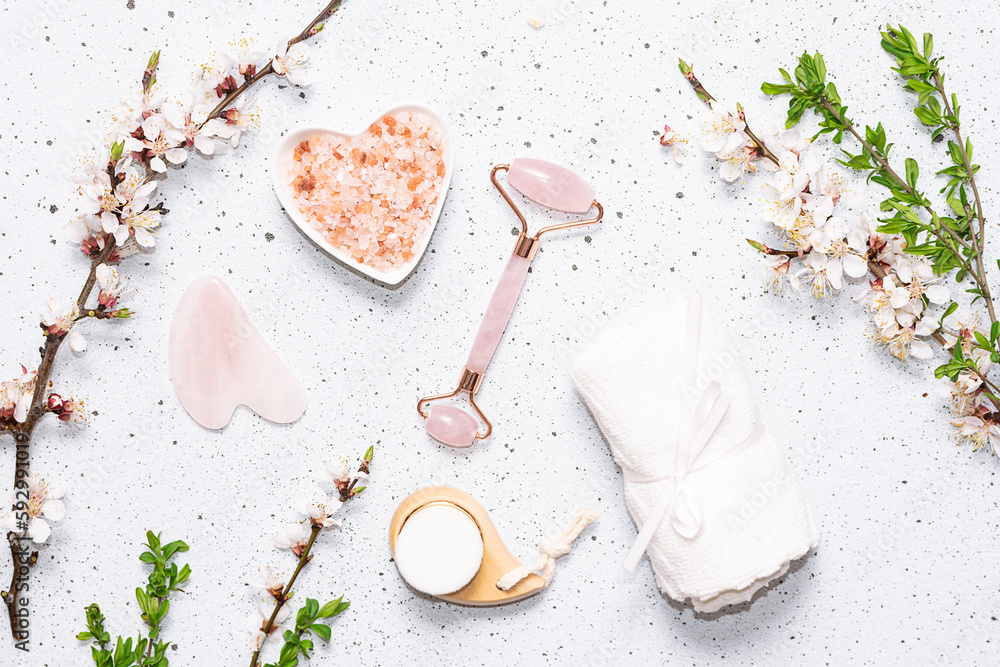 Face care cosmetic products such as serum, mask, cream, balm and facial brush on white marble background with fresh aromatic blooming apricot branches top view. Natural cosmetic concept. Face care cosmetic products such as serum, mask, cream, balm and facial brush on white marble background with fresh aromatic blooming apricot branches top view. Natural cosmetic concept.