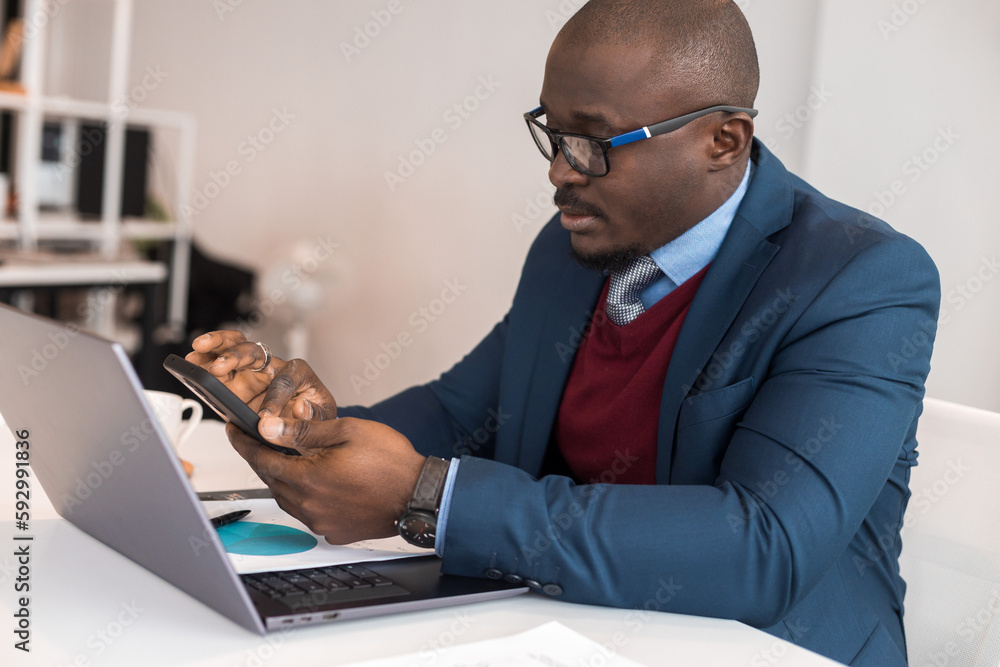 A black African American businessman in a business suit works at a laptop. Self-development and distance learning A black African American businessman in a business suit works at a laptop. Self-development and distance learning