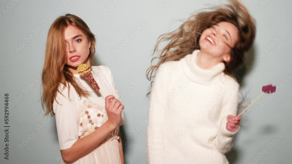 Two young beautiful woman singing with props fake microphone. Trendy girls in casual summer clothes. Positive female emotion facial expression body language with big lips. Funny models isolated Two young beautiful woman singing with props fake microphone. Trendy girls in casual summer clothes. Positive female emotion facial expression body language with big lips. Funny models isolated