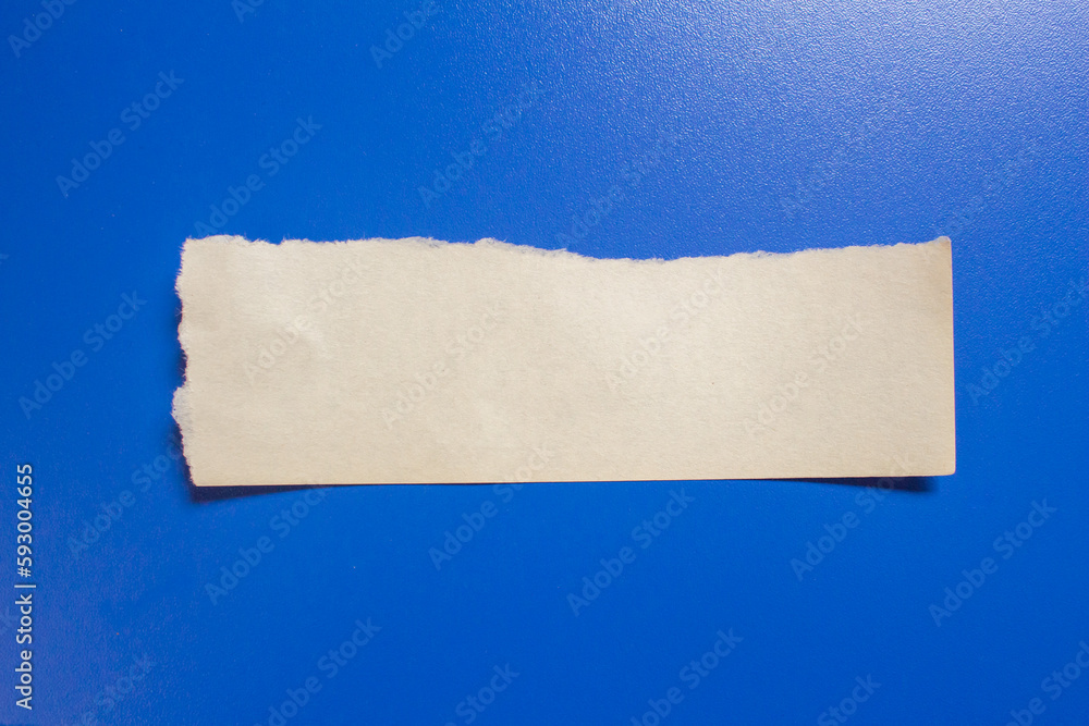 Ripped paper piece isolated on a blue background. Torn paper with copy space for text. Ripped paper piece isolated on a blue background. Torn paper with copy space for text.