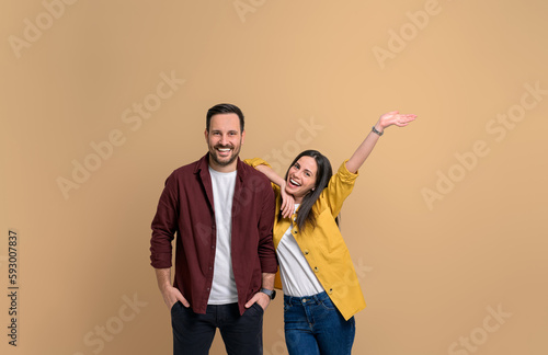Фотография Cheerful young girlfriend with hand raised screaming and leaning on handsome boyfriend