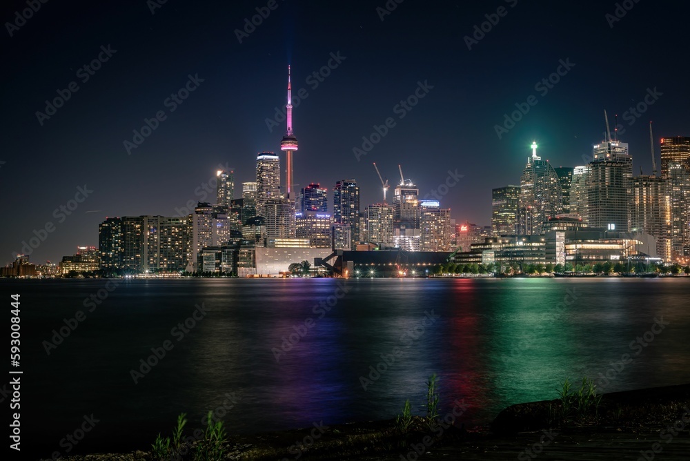 Image of a cityscape of Downtown Toronto during night with colorful lights and Lake Ontario