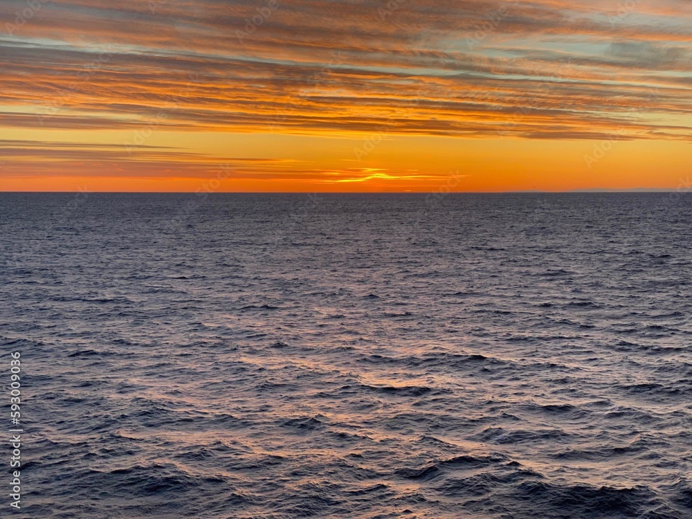 Obraz premium Die Sonne geht unter nach einem sonnigen Wintertag über dem Skagerrak. Der Himmel ist orange gefärbt. Auf dem Meer sorgt das spärlichere Licht für sanfte Schatten in der Nähe der schwedischen Küste.