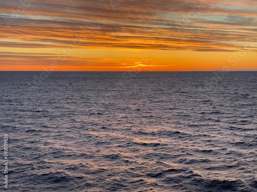 Die Sonne geht unter nach einem sonnigen Wintertag   ber dem Skagerrak. Der Himmel ist orange gef  rbt. Auf dem Meer sorgt das sp  rlichere Licht f  r sanfte Schatten in der N  he der schwedischen K  ste.