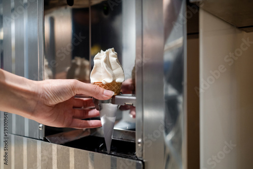 Hand taking the Automated soft serve ice cream at the dispenser in cafe