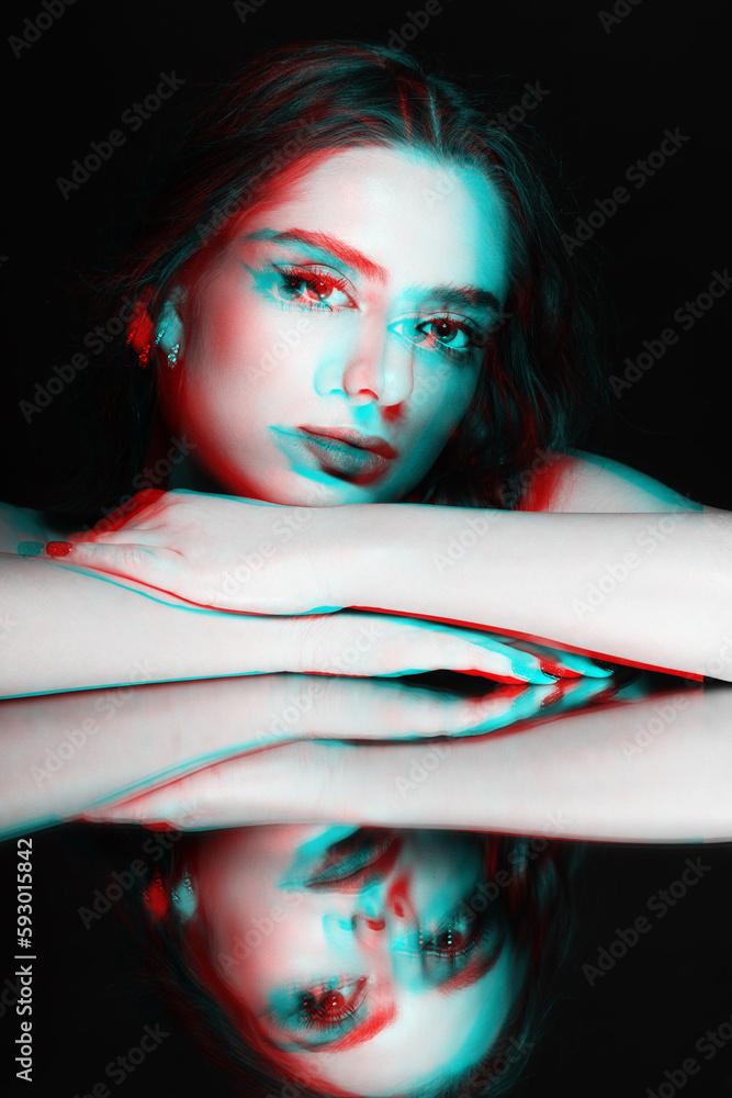 Woman studio portrait. Model placed head on hands. Mirror reflection of
