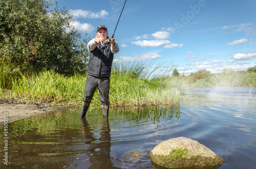 Fisherman in a hat on the river bank