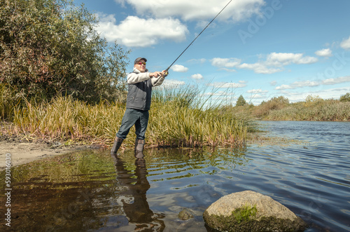 Man catching fish, pulling rod while fishing.