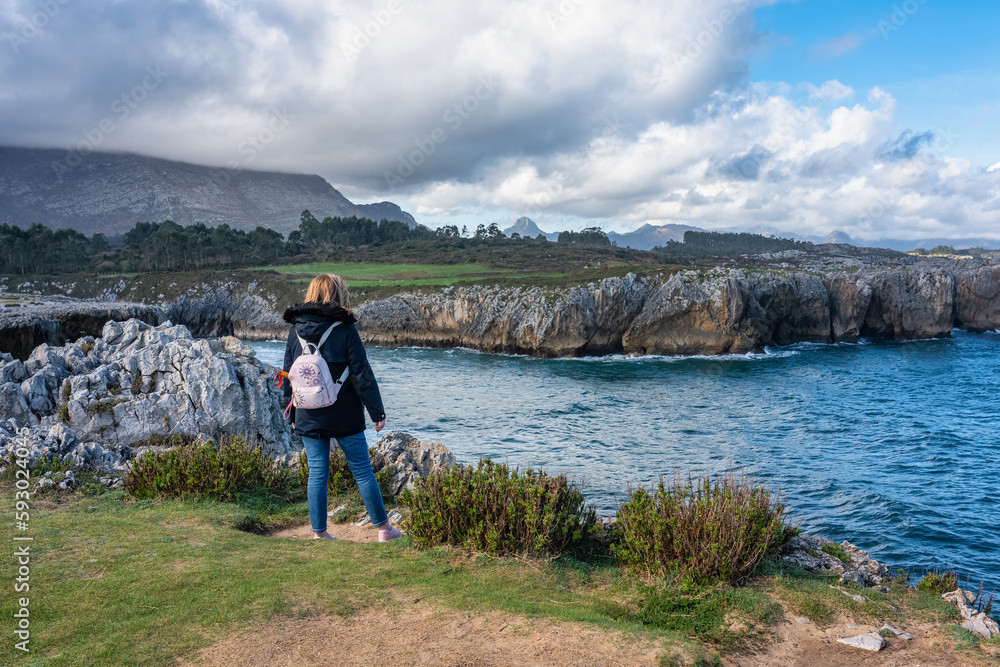 Woman contemplating the idyllic landscape from a cliff in northern Spain, Asturias.