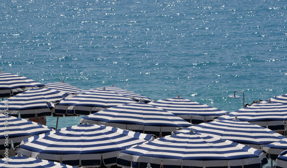 Parasols blancs et bleus et mer bleue sur une plage privée. Côte d'azur, France - obrazy, fototapety, plakaty 