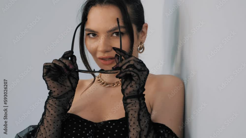 High fashion portrait of young beautiful brunette woman wearing nice trendy summer polka-dot dress and gloves. Sexy fashion model posing near light blue wall in studio. Fashionable female High fashion portrait of young beautiful brunette woman wearing nice trendy summer polka-dot dress and gloves. Sexy fashion model posing near light blue wall in studio. Fashionable female