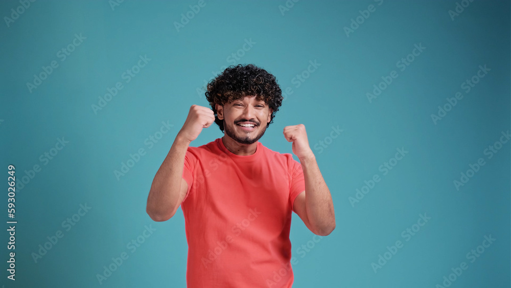 Extremely excited overjoyed man with beard shouting making yes gesture, amazed with his victory, triumph. in coral t-shirt on blue studio background Extremely excited overjoyed man with beard shouting making yes gesture, amazed with his victory, triumph. in coral t-shirt on blue studio background