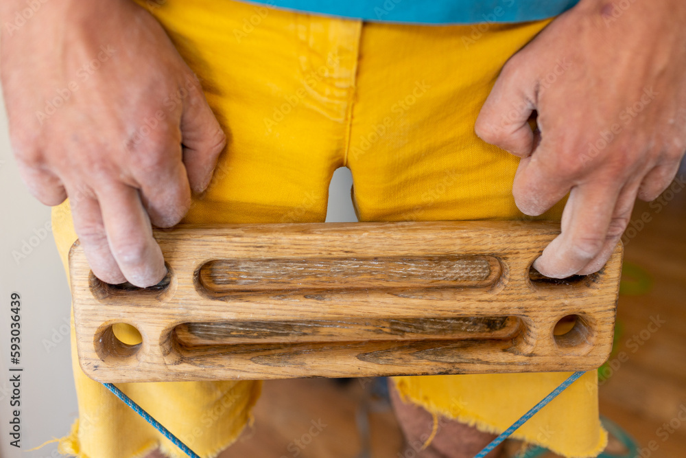 strong male hand of a rock climber holds a board for training finger