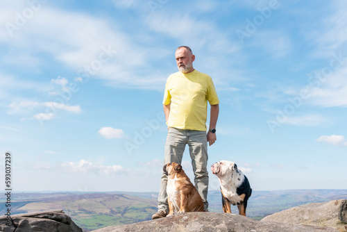 Foto A happy pensioner with English bulldogs on top of mountain, going for a walk in Peak District on Autumn day
