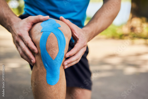 Obraz na plátně Close-up of male runner holding injured knee with kinesiology tape