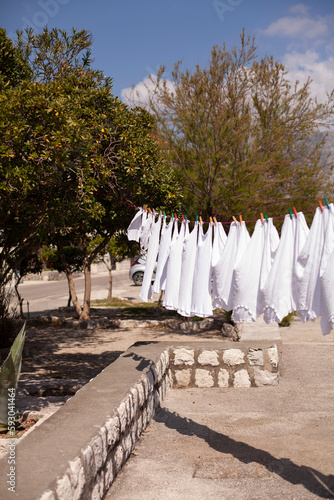 Fresh clean white clothing hanging outside in wind and sun to dry. Laundry drying on the rope outside on a sunny day near the sea.
