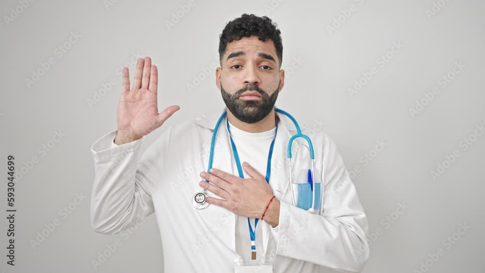 Young hispanic man doctor making an oath with hand on chest over isolated white background Young hispanic man doctor making an oath with hand on chest over isolated white background