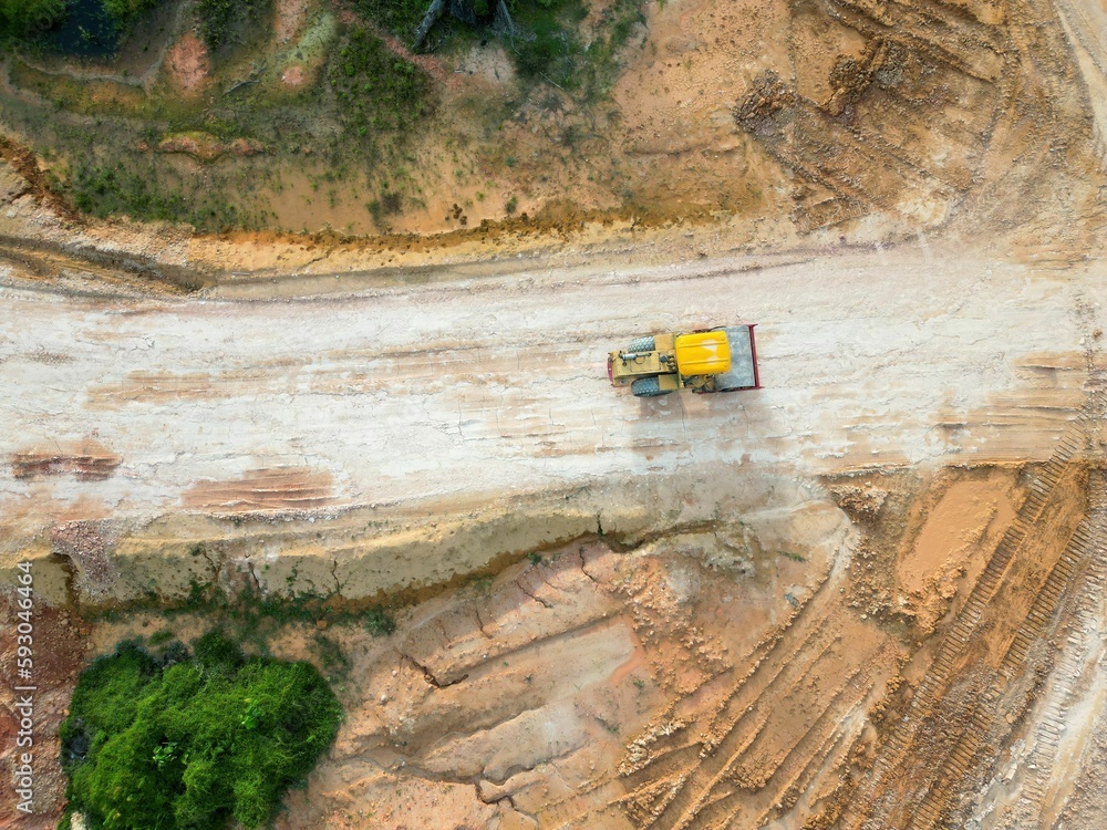 Aerial top view of a bulldozer cultivating a field of an oil palm plantation Aerial top view of a bulldozer cultivating a field of an oil palm plantation