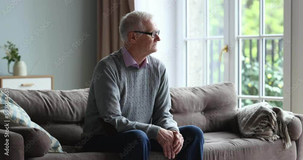 Pensive lonely old retired man sitting on couch alone, sighing, looking at window away in deep thought, thinking over serious health problems, bad news, feeling apathy, suffering from mental disorder Pensive lonely old retired man sitting on couch alone, sighing, looking at window away in deep thought, thinking over serious health problems, bad news, feeling apathy, suffering from mental disorder