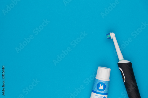 Brosse à dent électrique et tube de dentifrice sur fond bleu uni avec espace pour du texte photo