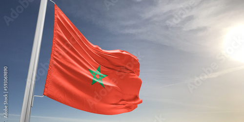 Morocco national flag cloth fabric waving on beautiful sky grey Background.