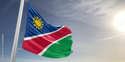 Namibia national flag cloth fabric waving on beautiful sky grey Background.