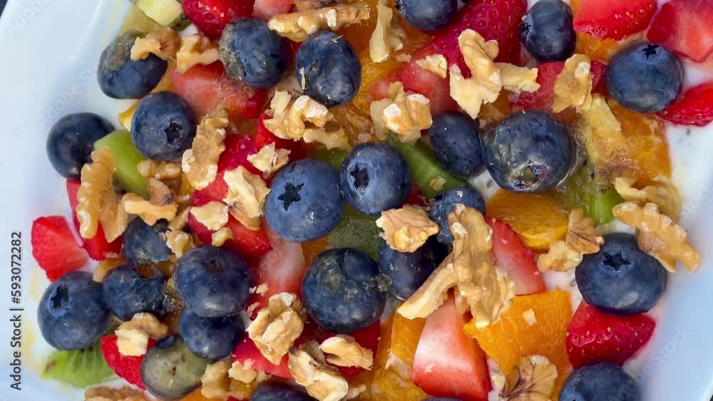 Healthy breakfast strawberries, raspberries, blueberries, kiwi, orange, nuts with honey and yogurt on plate. Healthy and delicious food. High quality 4k footage Healthy breakfast strawberries, raspberries, blueberries, kiwi, orange, nuts with honey and yogurt on plate. Healthy and delicious food. High quality 4k footage