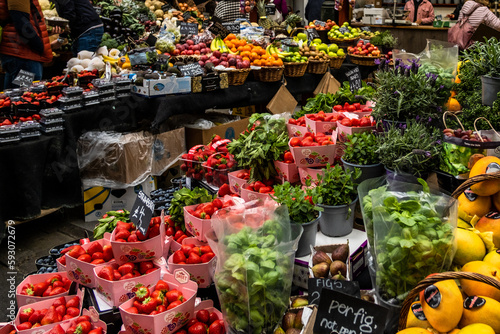 Strawberries and herbs at the market with other fruits and vegetables in the background