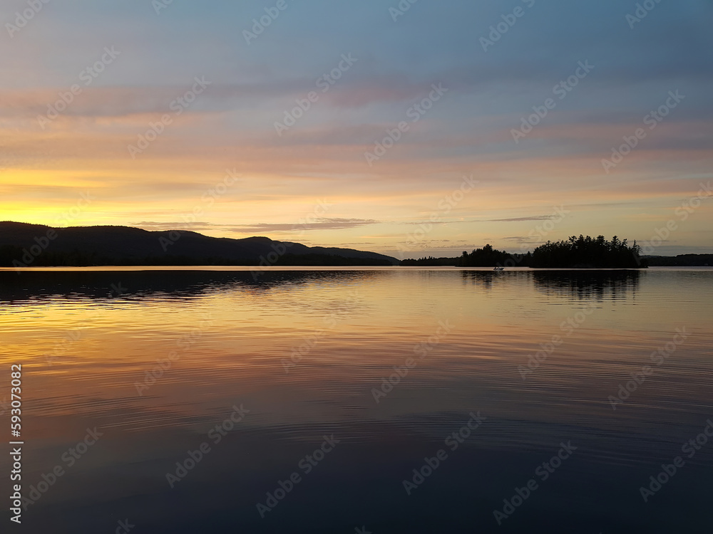 Fishermen in a small boat at sunset on a calm lake
