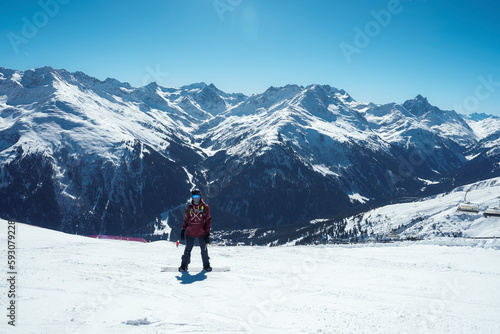 Tourist with snowboard on snow covered mountain with beautiful landscape and sky in background during vacation, winter holiday travel concept