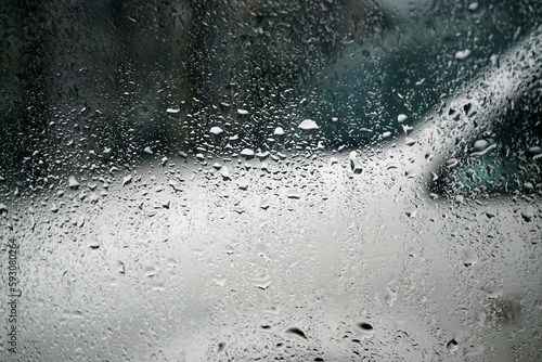 Abstraktes Motiv mit beschlagener Glasscheibe und Regentropfen vor weißem Auto auf Parkplatz in Stadt bei Regen am Nachmittag im Frühling