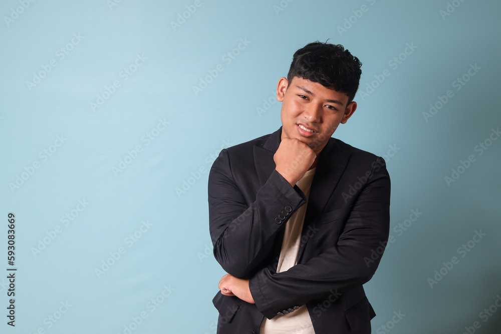 Portrait of young Asian business man in casual suit thingking while smiling. Isolated image on blue background Portrait of young Asian business man in casual suit thingking while smiling. Isolated image on blue background