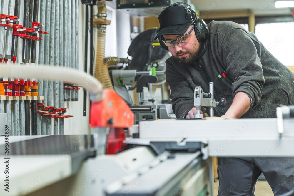 Carpenter in protective glasses using electric table saw ti properly cut wooden plank. Professional woodworking equipment. High quality photo Carpenter in protective glasses using electric table saw ti properly cut wooden plank. Professional woodworking equipment. High quality photo