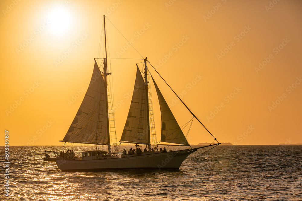 Sailboat with unidentifiable silhouettes of tourists enjoying the Sunset in Key West, Florida.