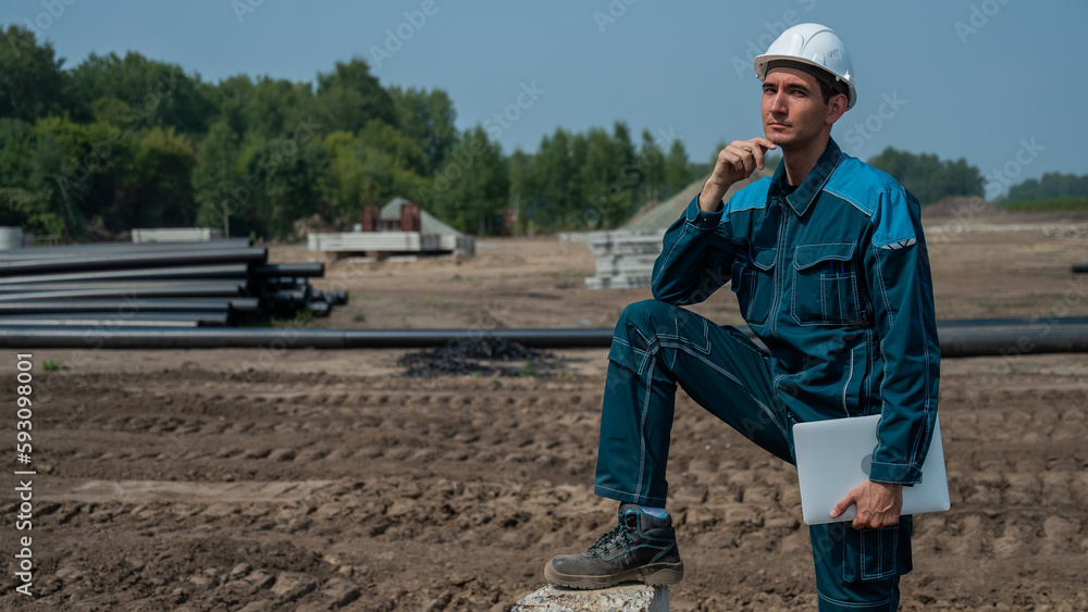 Caucasian male builder in hardhat holding laptop at construction site. Caucasian male builder in hardhat holding laptop at construction site.