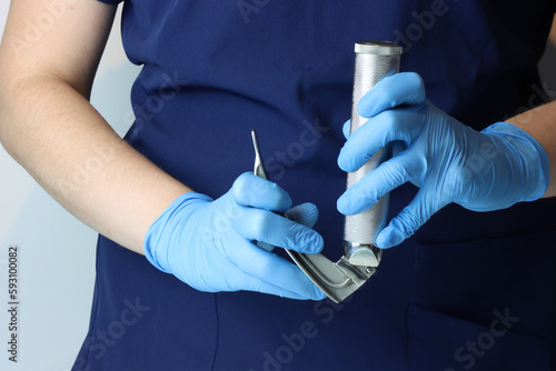 Health care professional wearing surgical gloves opening a laryngoscope to be use in an intubation photo