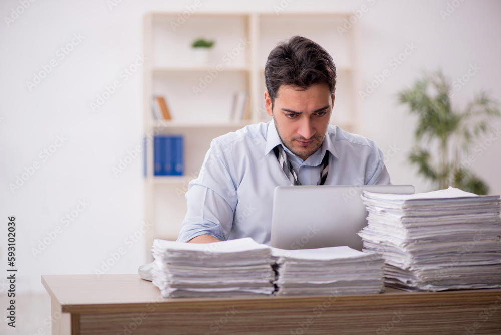 Young male employee and too much work in the office Young male employee and too much work in the office