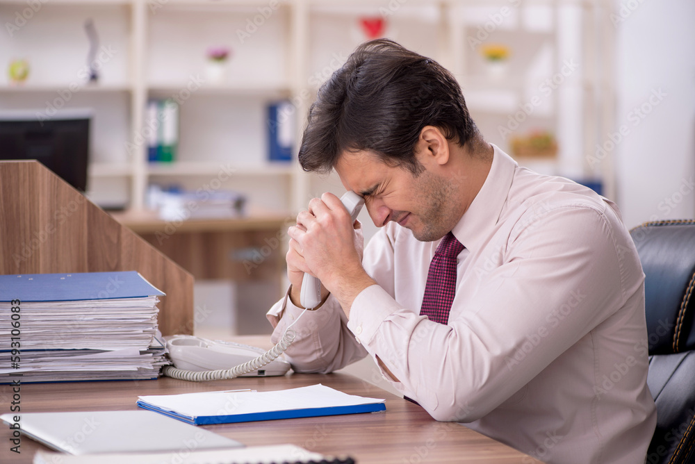 Young male employee and too much work in the office