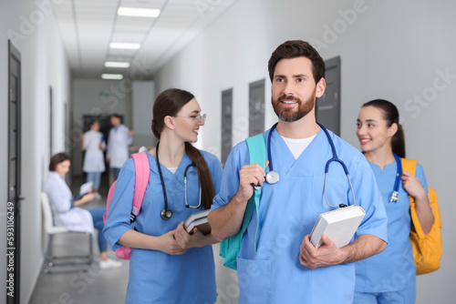 Smart medical student with book in college hallway
