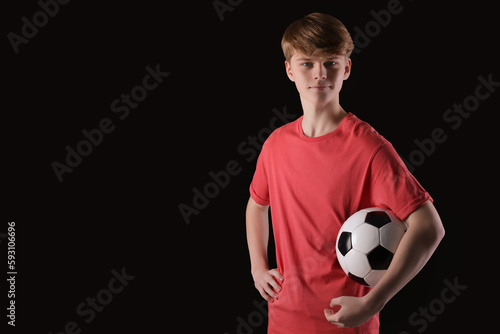Teenage boy with soccer ball on black background. Space for text © New Africa