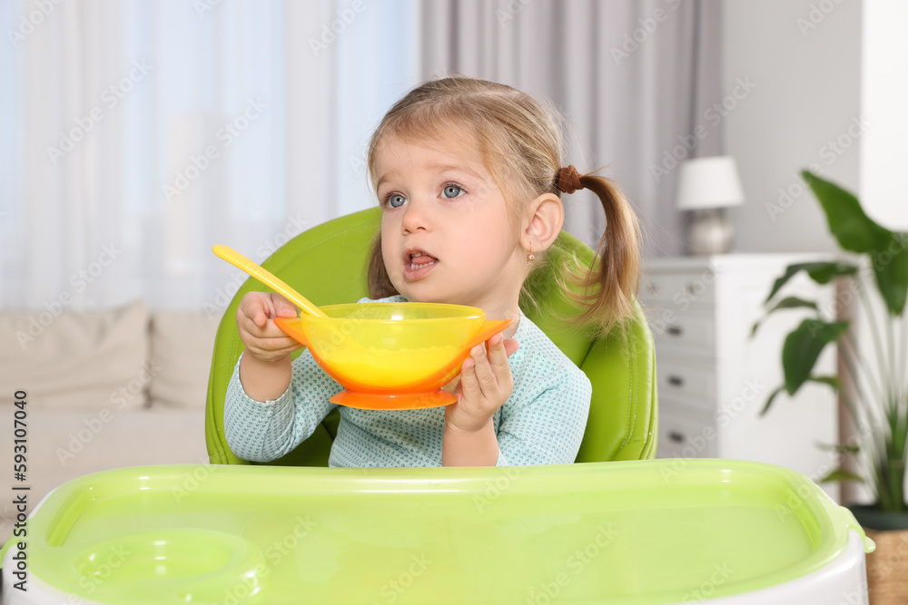 Cute little child with bowl of tasty yogurt in high chair indoors Cute little child with bowl of tasty yogurt in high chair indoors