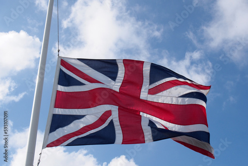 British union flag flaying against a blue cloudy sky in a flag pole